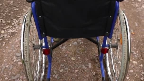환자의 도움을 기다리며 길가에 서 있는 텅 빈 휠체어. 야외에 주차 된 장애 인을 위한 휠체어. 장애가 있는 사람을 위해 사용 할 수있다. 의료 상의 개념. — 비디오