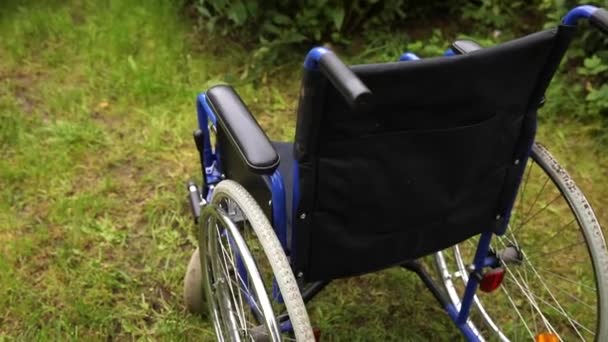 Lege rolstoel in ziekenhuispark wachtend op patiëntenzorg. Rolstoel voor personen met een handicap geparkeerd buiten. Toegankelijk voor personen met een handicap. Gezondheidszorg medisch concept. — Stockvideo