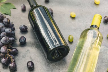 Şişe kırmızı ve beyaz şarap, yeşil şarap, şarap kadehi ve olgun üzümlü eskimiş taş masa arkaplanı. Şarap dükkanı şarap dükkanı ya da şarap tatma konsepti.