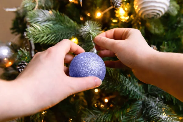 Woman hands decorating Christmas tree with ornaments ball colored in trendy color of year 2022 Very Peri background. Inspired by using color 17-3938, Color of the year concept. — Stock Photo, Image