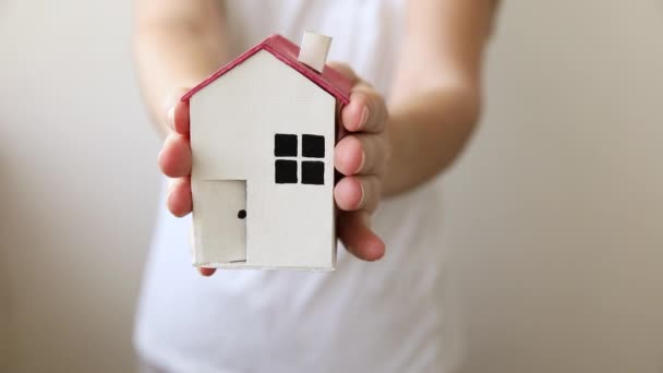 Kvinna hand håller leksak modell hus isolerad på vit bakgrund. Fastighetslån fastighetsförsäkring dröm hem koncept. Erbjudande om köp hyreshus, familjeliv, företagsfastigheter. — Stockvideo