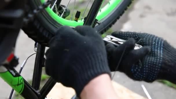 Mecánico de bicicletas reparaciones hombre bicicleta en taller de reparación de bicicletas, al aire libre. Mano de ciclista ciclista examina, fija el sistema de transmisión de ciclo moderno. Mantenimiento de bicicletas, concepto de tienda de deporte. — Vídeo de stock