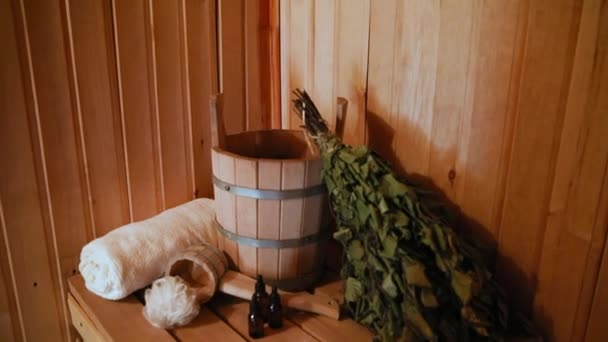 俄罗斯传统的老澡堂SPA概念。室内细节芬兰桑拿蒸汽房与传统桑拿配件设置盆栽扫帚香油。放松乡村洗澡水的概念. — 图库视频影像