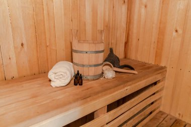 Geleneksel eski Rus hamamı SPA konsepti. Finlandiya sauna saunasında geleneksel sauna aksesuarları ve havlunun aromalı yağ kepçesi kullanılmış. Rahatlayın köy banyosu konsepti.