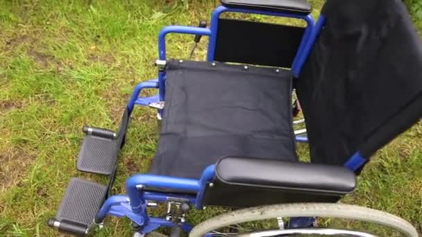 Порожній інвалідний візок стоїть у лікарняному парку, чекаючи на пацієнтські послуги. Колісний стілець для людей з інвалідністю, припаркований на відкритому повітрі. Доступний для людей з інвалідністю. Медична концепція охорони здоров'я . — стокове відео