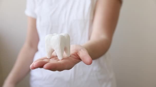 Sağlık diş sağlığı konsepti. Beyaz arka planda izole edilmiş beyaz, sağlıklı bir diş modelini tutan kadın. Diş beyazlatma, diş temizliği, diş bakımı, dişçi günü.. — Stok video
