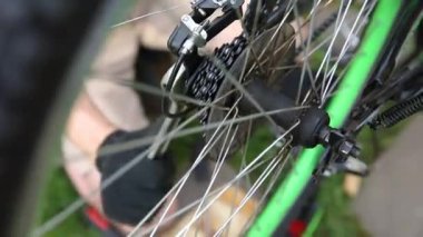 Bisikletli tamirci dışarıdaki bisiklet tamirhanesinde bisiklet tamir ediyor. Bisikletçinin eli modern bisiklet iletim sistemini inceliyor, tamir ediyor. Bisiklet bakımı, spor mağazası konsepti.
