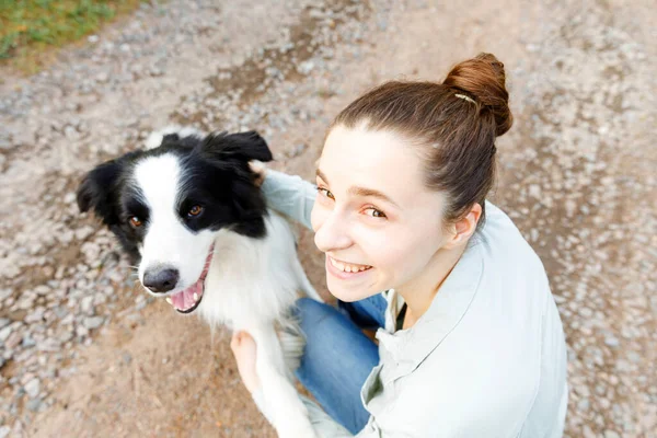 Lächelnde junge attraktive Frau, die mit niedlichen Hundewelpen Border Collie auf sommerlichem Outdoor-Hintergrund spielt. Mädchen umarmt umarmende Hundefreundin. Haustierpflege und Tierkonzept. — Stockfoto