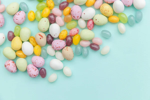 Happy Easter concept. Preparation for holiday. Easter candy chocolate eggs and jellybean sweets isolated on trendy pastel blue background. Simple minimalism flat lay top view copy space. — Stock Photo, Image