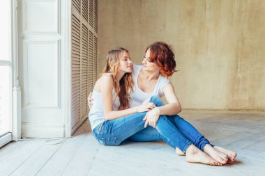 Çocuğunu kucaklayan genç bir anne. Kadın ve genç kız, gri duvarın yanındaki beyaz yatak odasında dinleniyorlar. Evde mutlu bir aile. Genç anne kızıyla oynuyor..