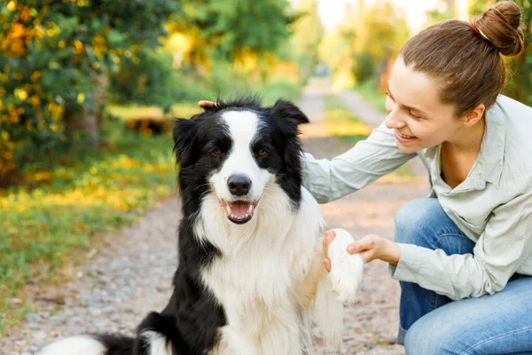 Lachende jonge aantrekkelijke vrouw spelen met schattige puppy hondengrens collie op zomer outdoor achtergrond. Meisje dat knuffelende hondenvriend omhelst. Dierenverzorging en dierenwelzijn. — Stockfoto