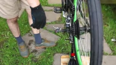 Bisikletli tamirci dışarıdaki bisiklet tamirhanesinde bisiklet tamir ediyor. Bisikletçinin eli modern bisiklet iletim sistemini inceliyor, tamir ediyor. Bisiklet bakımı, spor mağazası konsepti.