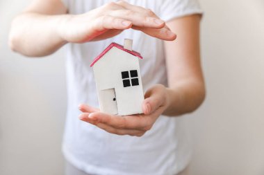 Beyaz arka planda izole edilmiş oyuncak model evi tutan kadın. Gayrimenkul ipoteği sigorta hayali ev konsepti. Kiralık ev, aile hayatı, iş yeri gayrimenkul teklifi.