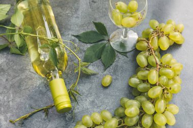 Şişe beyaz şarap, yeşil şarap, şarap kadehi ve eski gri taş masa zemininde olgun üzüm. Şarap dükkanı şarap dükkanı ya da şarap tatma konsepti.