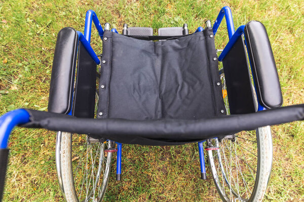 Empty wheelchair standing in hospital park waiting for patient services. Wheel chair for person with disability parked outdoor. Accessible for person with disability. Health care medical concept.
