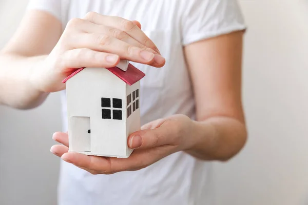 흰 배경에 고립된 장난감 모델 하우스를 손에 쥐고 있는 여성. 부동산 담보 대출 부동산 보험은 홈 개념을 꿈꾸고 있습니다. 임대 주택, 가정생활, 사업 상의 부동산을 매입하겠다는 제안. — 스톡 사진