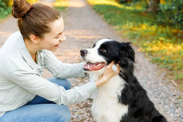 Lachende jonge aantrekkelijke vrouw spelen met schattige puppy hondengrens collie op zomer outdoor achtergrond. Meisje dat knuffelende hondenvriend omhelst. Dierenverzorging en dierenwelzijn. — Stockfoto