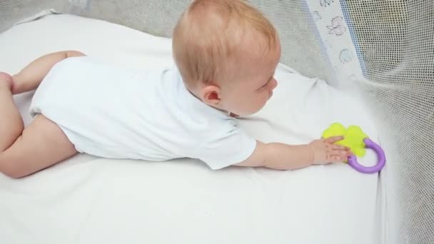 Drăguţă fetiţă nou-născută întinsă pe burtă pe o pătură albă în playpen. Copilul se distrează acasă în interior. Copilul se odihneşte jucându-se de-a învăţa să se târască. Copilăria maternă Conceptul fericit al copilului. — Videoclip de stoc