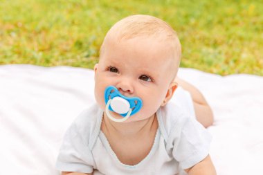Güneşli bir yaz gününde çimenlikte, göbeğin üzerinde uzanan tatlı küçük bir kız. Bebek dışarıda çok eğleniyor. Bebek bebek dinleniyor, emeklemeyi öğreniyor. Annelik mutlu çocuk konsepti.