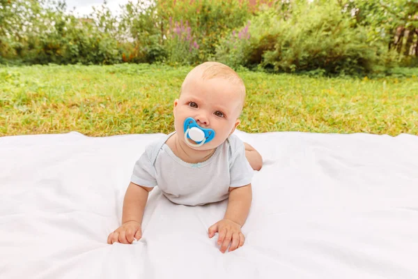 Cute little newborn girl lying on tummy on blanket in lawn on sunny summer day outdoor. Infant having fun outdoors. Infant baby child resting playing learning to crawl. Motherhood happy child concept. — Stock Photo, Image