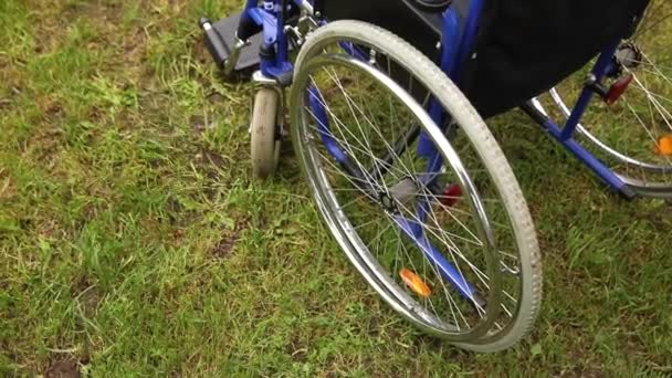 Silla de ruedas vacía de pie en el parque del hospital esperando los servicios del paciente. Silla de ruedas para personas con discapacidad aparcada al aire libre. Accesible para personas con discapacidad. Concepto médico de atención médica. — Vídeos de Stock