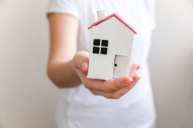 Beyaz arka planda izole edilmiş oyuncak model evi tutan kadın. Gayrimenkul ipoteği sigorta hayali ev konsepti. Kiralık ev, aile hayatı, iş yeri gayrimenkul teklifi.