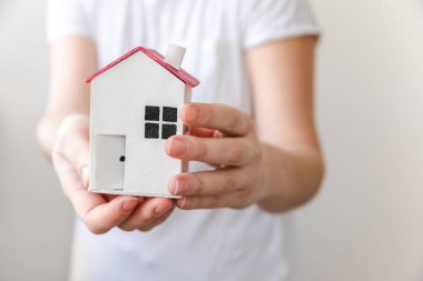 Beyaz arka planda izole edilmiş oyuncak model evi tutan kadın. Gayrimenkul ipoteği sigorta hayali ev konsepti. Kiralık ev, aile hayatı, iş yeri gayrimenkul teklifi.