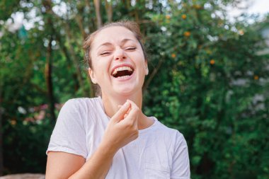Dışarıda gülümseyen genç bir kadın. Güzel esmer kız parkta dinleniyor ya da bahçe yeşili arka planda. Yazın özgür ve mutlu bir kadın. Özgürlük mutluluğu tasasız mutlu insanlar konsepti.
