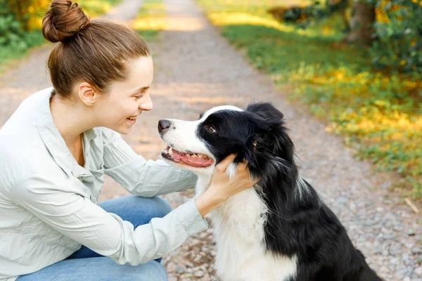 Lachende jonge aantrekkelijke vrouw spelen met schattige puppy hondengrens collie op zomer outdoor achtergrond. Meisje dat knuffelende hondenvriend omhelst. Dierenverzorging en dierenwelzijn. — Stockfoto