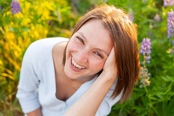 Jovem mulher sorrindo ao ar livre. Menina bonita morena descansando no campo de verão com flores selvagens florescendo fundo. Mulher feliz livre no verão. Liberdade felicidade despreocupado conceito de pessoas felizes — Fotografia de Stock