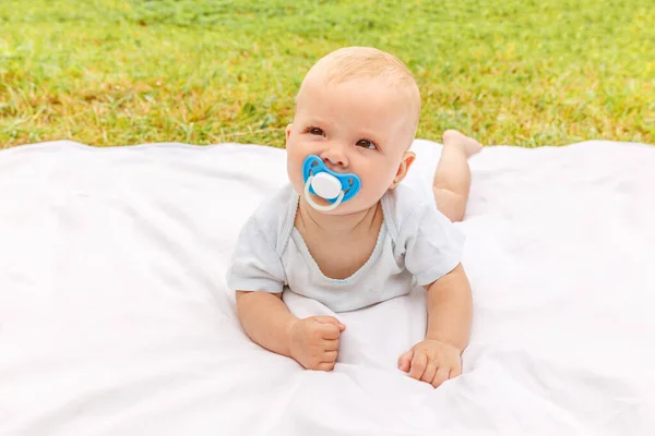 Carina bambina appena nata sdraiata sulla pancia sulla coperta nel prato durante la soleggiata giornata estiva all'aperto. Bambino che si diverte all'aperto. Bambino bambino bambino che riposa giocando imparare a strisciare. Maternità concetto bambino felice. — Foto Stock