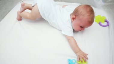 Bebek parkında beyaz bir battaniyenin üzerinde göbeğinde yatan tatlı küçük bir kız. Bebek evde eğleniyor, evde. Bebek bebek dinleniyor, emeklemeyi öğreniyor. Annelik bebekliği mutlu çocuk konsepti.