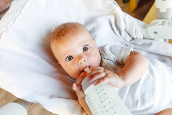 젖병에서 우유를 마시고 하얀 배경에 카메라를 보고 있는 귀여운 신생아. 아기는 집 침대에 누운 젖먹이의 영양분을 빨아먹는다. 어머니의 행복 한 자녀 개념. — 스톡 사진