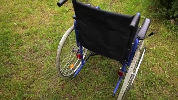 Cadeira de rodas vazia em pé no parque hospitalar à espera de atendimento ao paciente. Cadeira de rodas para pessoa com deficiência estacionada ao ar livre. Acessível para pessoas com deficiência. Conceito médico de saúde. — Vídeo de Stock