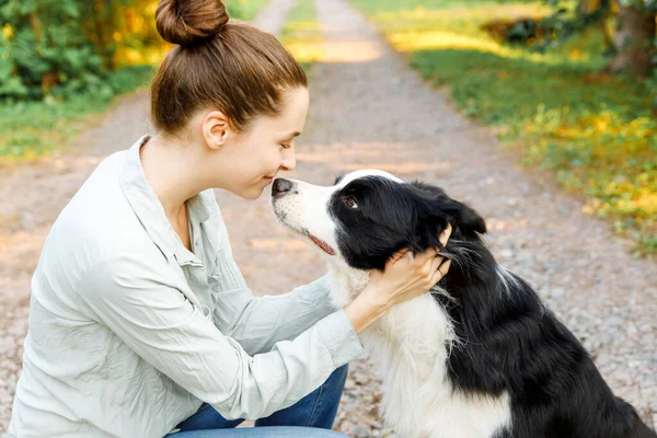 Lachende jonge aantrekkelijke vrouw spelen met schattige puppy hondengrens collie op zomer outdoor achtergrond. Meisje dat knuffelende hondenvriend omhelst. Dierenverzorging en dierenwelzijn. — Stockfoto