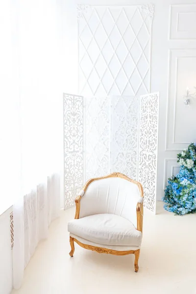 Belo luxo clássico branco brilhante quarto interior limpo em estilo barroco com grande janela, poltrona e composição de flores. — Fotografia de Stock