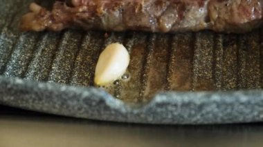 Profesyonel mutfakta ızgara tavada sarımsaklı etli biftek. Izgarada kızarmış biftek. Lezzetli, modern mutfak.