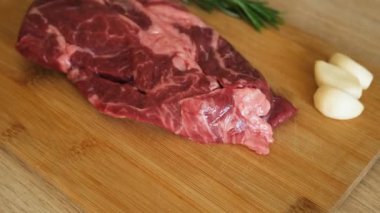 Sarımsak ve biberiyeli sulu et mutfaktaki ahşap kesme tahtasında pişirmeye hazır. Pişmemiş çiğ biftek ve sarımsak. Enfes, modern mutfağı kapatın.