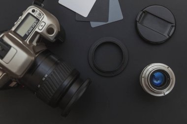 Fotoğrafçı işyeri. DSR kamera sistemi aksesuar ve siyah masa arkaplanındaki kamera temizleme seti. Hobi seyahat fotoğrafçılık konsepti. Düz üst görünüm