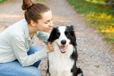 Gülümseyen genç ve çekici bir kadın yaz sezonu arka planında sevimli köpek yavrusu çoban köpeğiyle oynuyor. Kucaklayan köpek arkadaşını kucaklayan bir kız. Hayvan bakımı ve hayvan bakımı kavramı