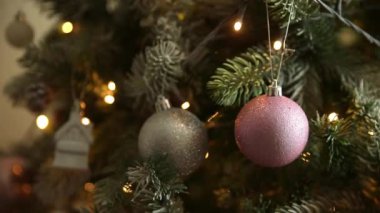Klasik yeni yıl ağacı, gümüş, beyaz, pembe süsleme oyuncakları, top ve çözünmüş çelenk ışıklarıyla süslenmiş. Modern klasik tatil tasarımı. Evde Noel arifesi