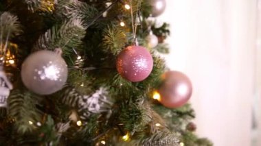 Klasik yeni yıl ağacı, gümüş, beyaz, pembe süsleme oyuncakları, top ve çözünmüş çelenk ışıklarıyla süslenmiş. Modern klasik tatil tasarımı. Evde Noel arifesi