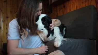 Gülümseyen genç bir kadın evdeki kanepede köpek yavrusu çoban köpeğiyle oynuyordu. Evcil köpek arkadaşı olan ev sahibi kız evde dinleniyor. İnsan ve hayvan arkadaşlığı kavramı