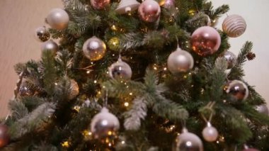 Klasik yeni yıl ağacı, gümüş, beyaz, pembe süsleme oyuncakları, top ve çözünmüş çelenk ışıklarıyla süslenmiş. Modern klasik tatil tasarımı. Evde Noel arifesi