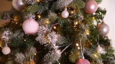 Klasik yeni yıl ağacı, gümüş, beyaz, pembe süsleme oyuncakları, top ve çözünmüş çelenk ışıklarıyla süslenmiş. Modern klasik tatil tasarımı. Evde Noel arifesi
