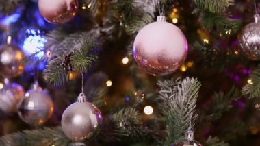 Klasik yeni yıl ağacı, gümüş, beyaz, pembe süsleme oyuncakları, top ve çözünmüş çelenk ışıklarıyla süslenmiş. Modern klasik tatil tasarımı. Evde Noel arifesi