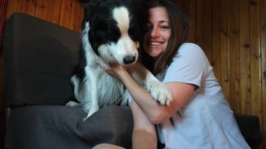 Gülümseyen genç bir kadın evdeki kanepede köpek yavrusu çoban köpeğiyle oynuyordu. Evcil köpek arkadaşı olan ev sahibi kız evde dinleniyor. İnsan ve hayvan arkadaşlığı kavramı