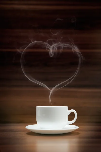 Taza de café con humo en forma de corazón sobre fondo de madera oscura —  Fotos de Stock