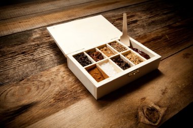 Assortment of spices in wooden box on old wooden table clipart
