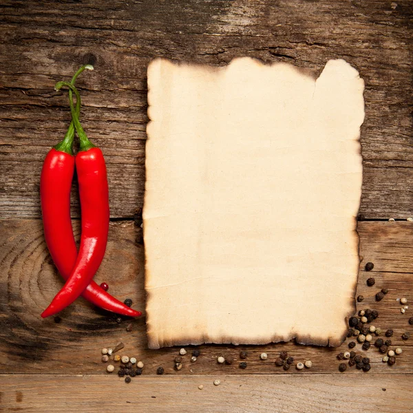 Chiles rojos picantes con la hoja de papel vieja —  Fotos de Stock